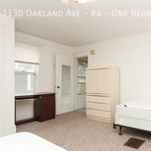 a bedroom with a bed, dresser, and wardrobe in an unfurnished apartment.
