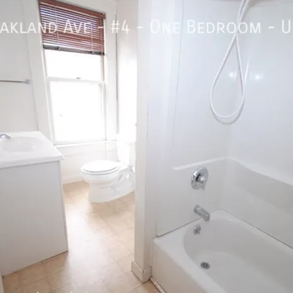 a white bathroom with a tub, toilet and sink.