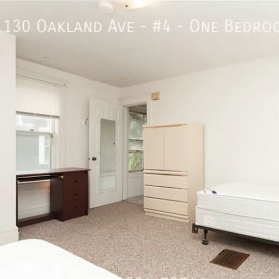a bedroom with a bed, dresser, and wardrobe in a property located at 1130 oakland ave, unit #4.
