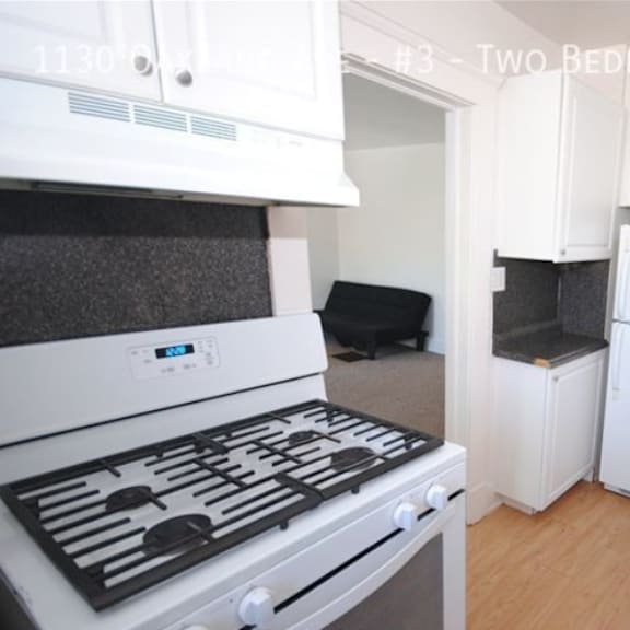 a white kitchen with a stove top oven and a refrigerator.