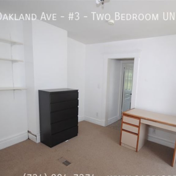 a room with a black dresser and a wooden desk in it.