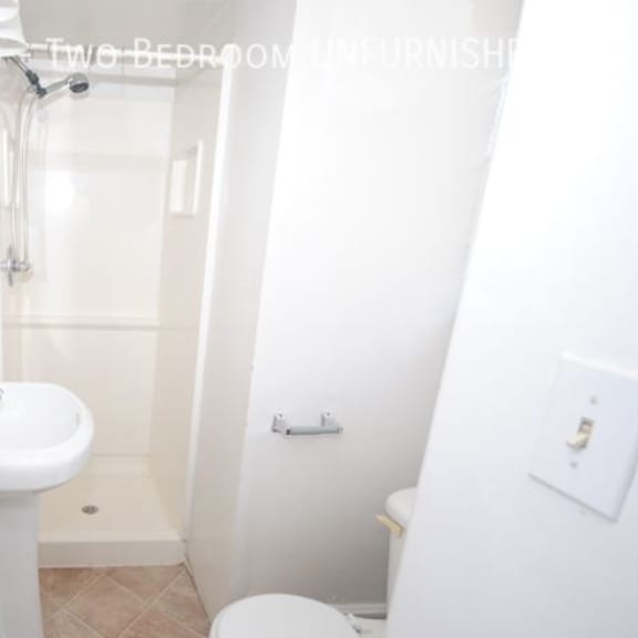 a white bathroom with a toilet, sink, and shower.