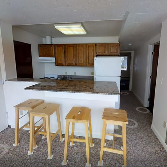 a kitchen with a white fridge and wooden stools.