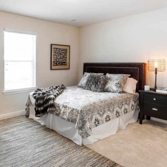 a bedroom with a bed, chair, and lamp.