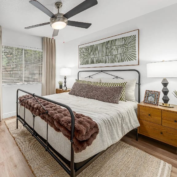 A bedroom with a bed, a ceiling fan, and a wooden dresser.