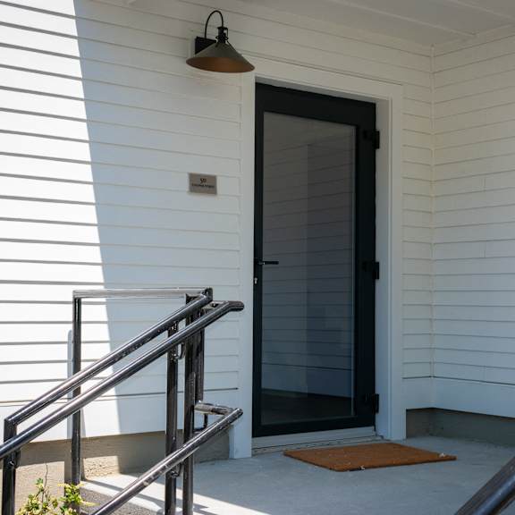 the front door of a white house with a black doorframe
