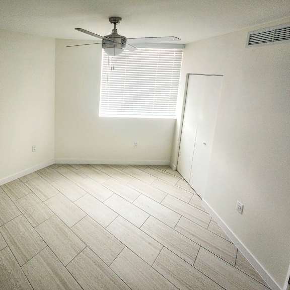 an empty room with a ceiling fan and a window at meridian point at goulds station in miami, fl, 33170