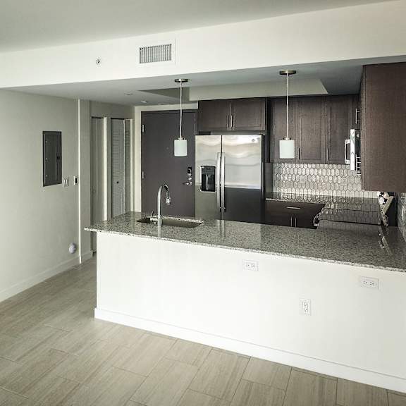 an open kitchen and living room with a granite counter top at meridian point at goulds station in miami, fl, 33170
