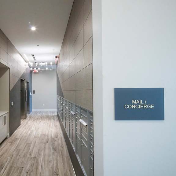 a long hallway with a sign that says "mail / concierge" on the wall.