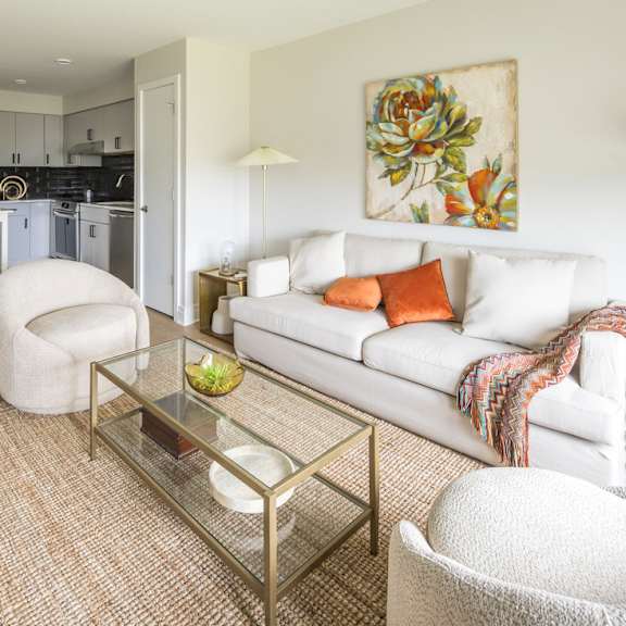 a modern living room with a white couch and a glass coffee table.