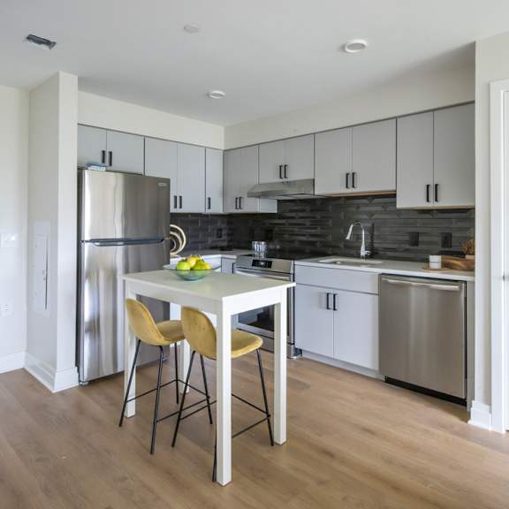 a kitchen with a table and chairs in front of a refrigerator.