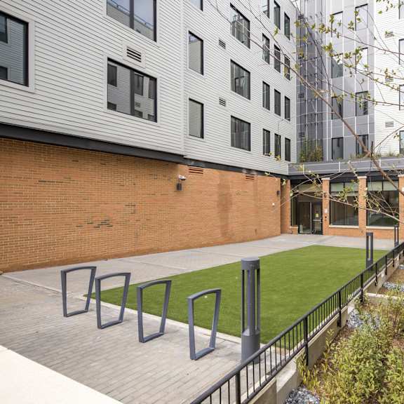 a courtyard with a green lawn and a brick wall.