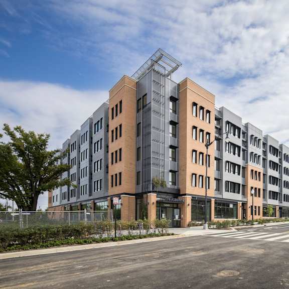 a modern apartment building with a glass entrance and a street in front.
