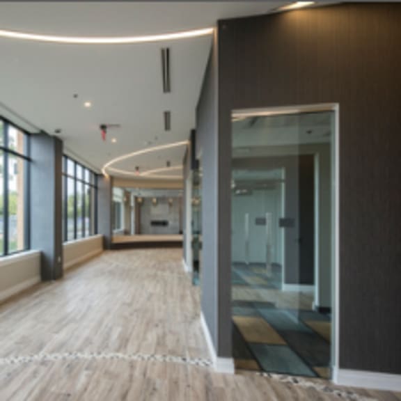 a long hallway with wood floors and windows on one side.