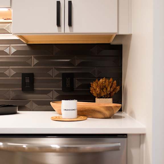 a small kitchen with white cabinets and a stainless steel refrigerator