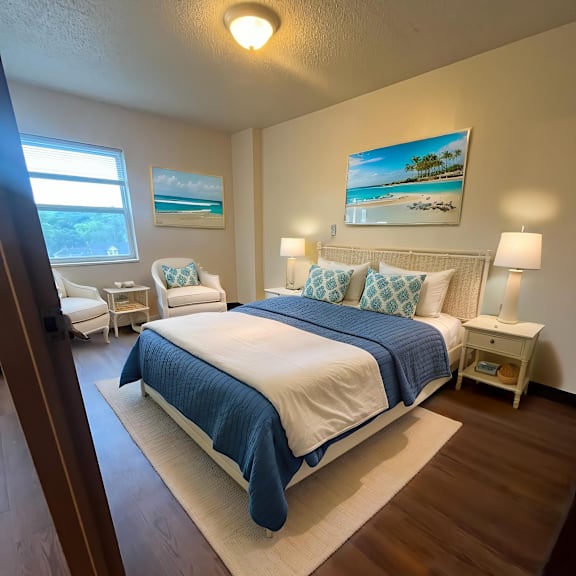 a bedroom with a bed, two chairs, and a painting on the wall.