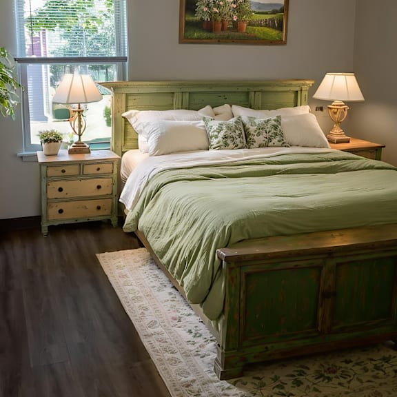 a bedroom with a green bed and a painting on the wall.