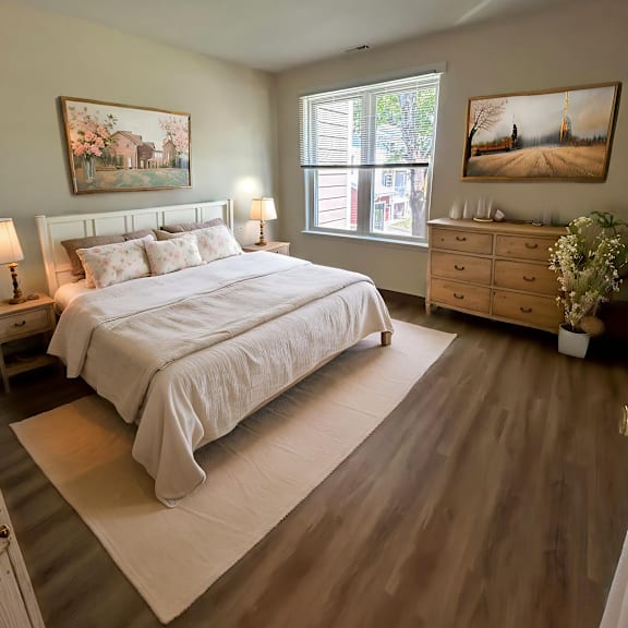 a bedroom with a large bed, a dresser, and two paintings on the wall.