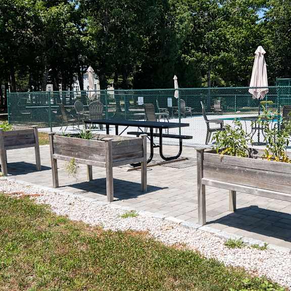 a wooden bench with a planter box on top is situated in a park.
