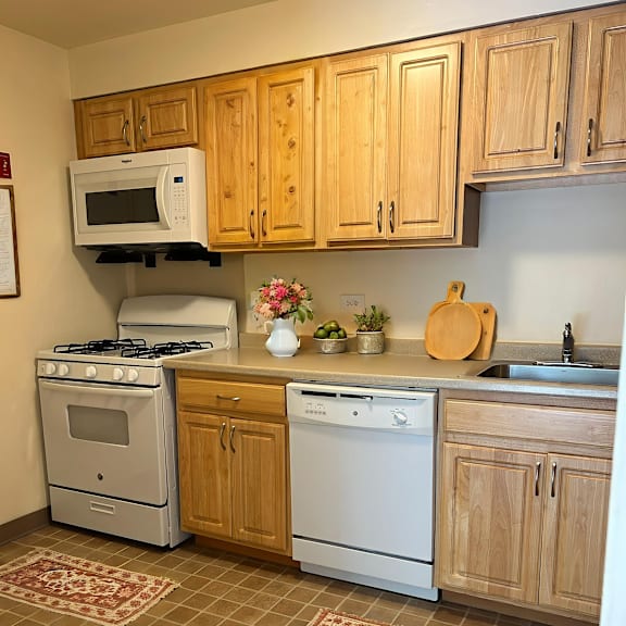 a kitchen with a white stove and oven, a microwave, and wooden cabinets.