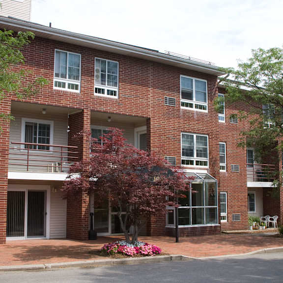 a red brick apartment building with a porch and a tree