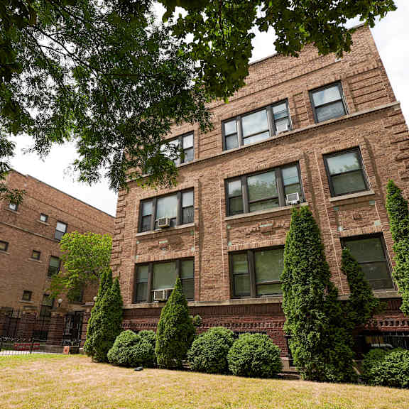a large brick building with a green lawn in front.