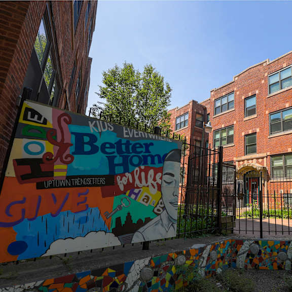 a brick building with a mural on the fence in front.
