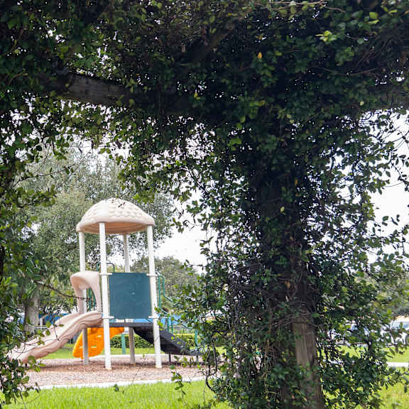a playground with a green slide and a white tower.