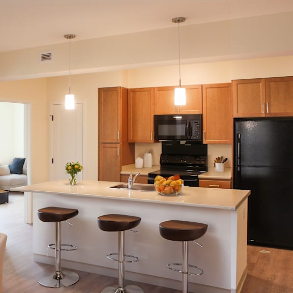 a kitchen with a black refrigerator, wooden cabinets, and a white island.