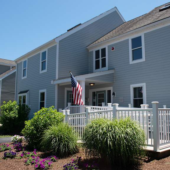 a blue house with a white fence and an flag