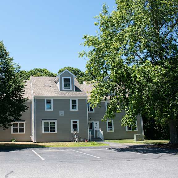 a large gray house with trees in a parking lot