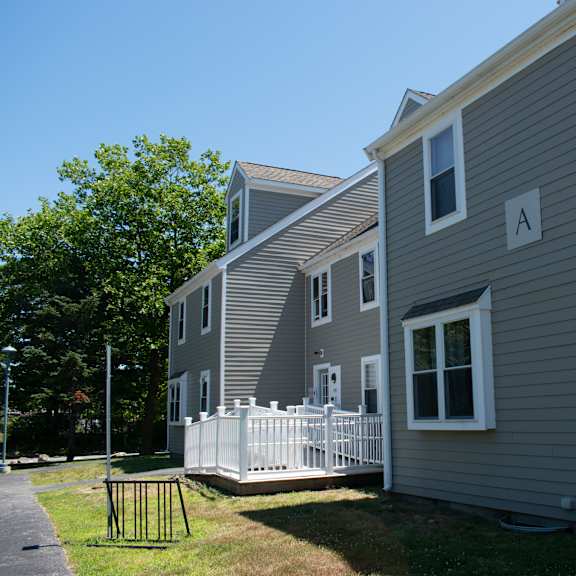 a gray house with a white porch and a white fence