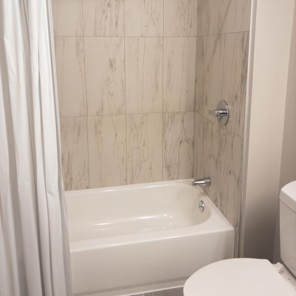 a white bathroom with a marble tile shower.