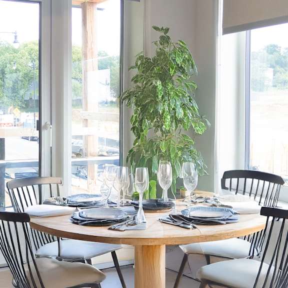 a dining table set with plates and glasses in front of a window.