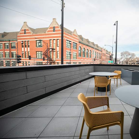 a patio with a table and chairs overlooking a brick building.