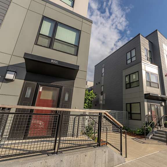a group of new apartment buildings with stairs and a sidewalk