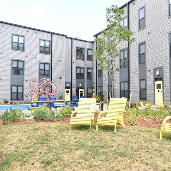 a group of yellow chairs in front of an apartment building