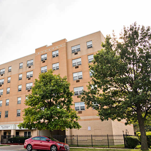 a red car is parked in front of a brick building.