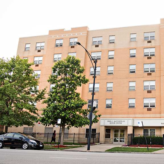 a large brick building with a black fence in front.