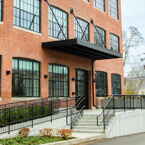 a red brick building with a black awning and a black metal fence.