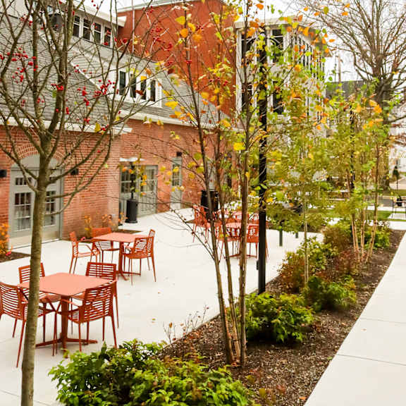a courtyard with tables and chairs and trees.
