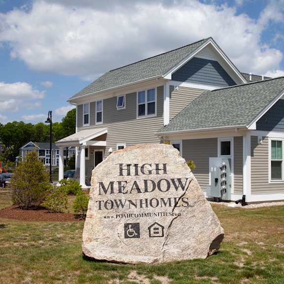 a large rock in front of a house with a sign for high meadow apartments