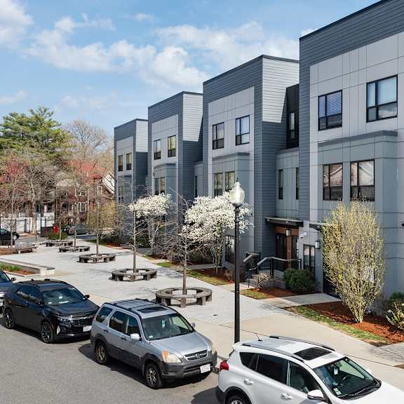 a row of modern townhouses with cars parked in front.