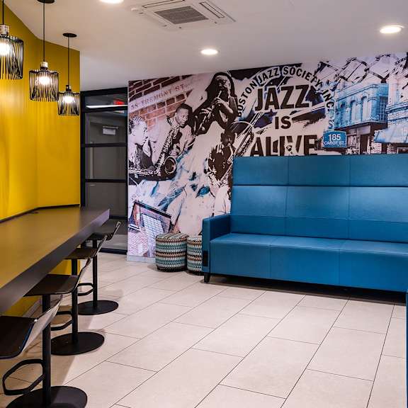a blue couch is in the middle of a room with a yellow wall and a mural on the wall.