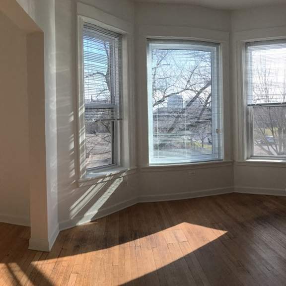 an empty living room with three windows and a wooden floor