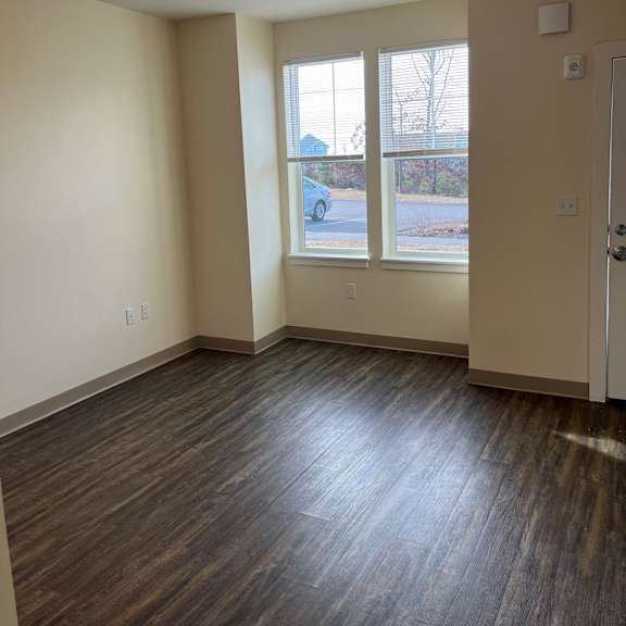 an empty living room with wood floors and a window