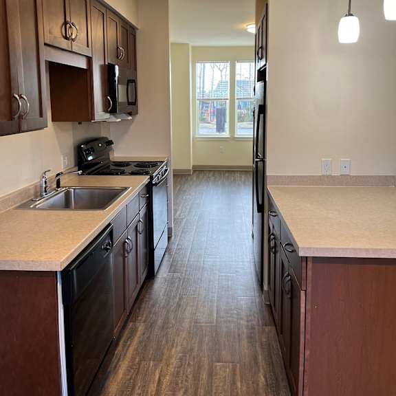 an empty kitchen with wood floors and wooden cabinets