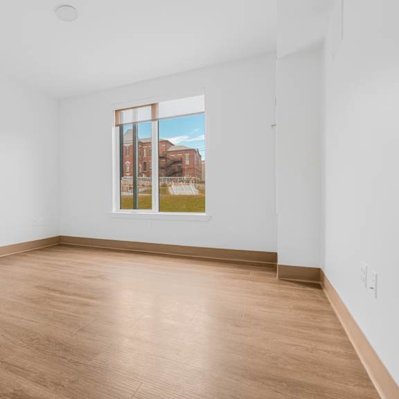 a room with white walls and wood floors and a large window