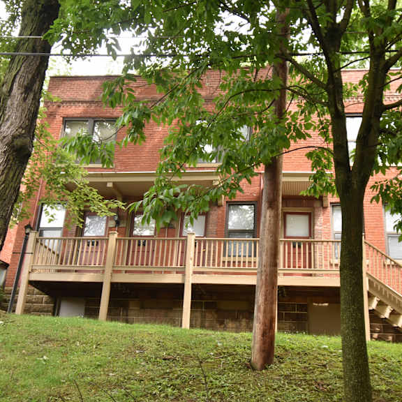 a red brick apartment building with a balcony and trees
