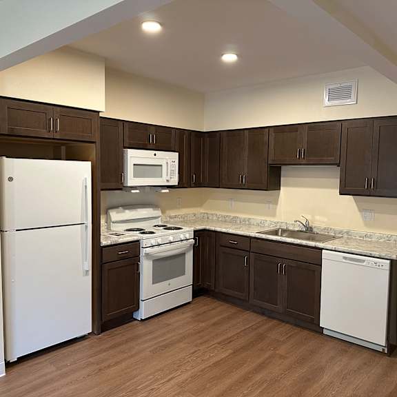a kitchen with white appliances and dark cabinets